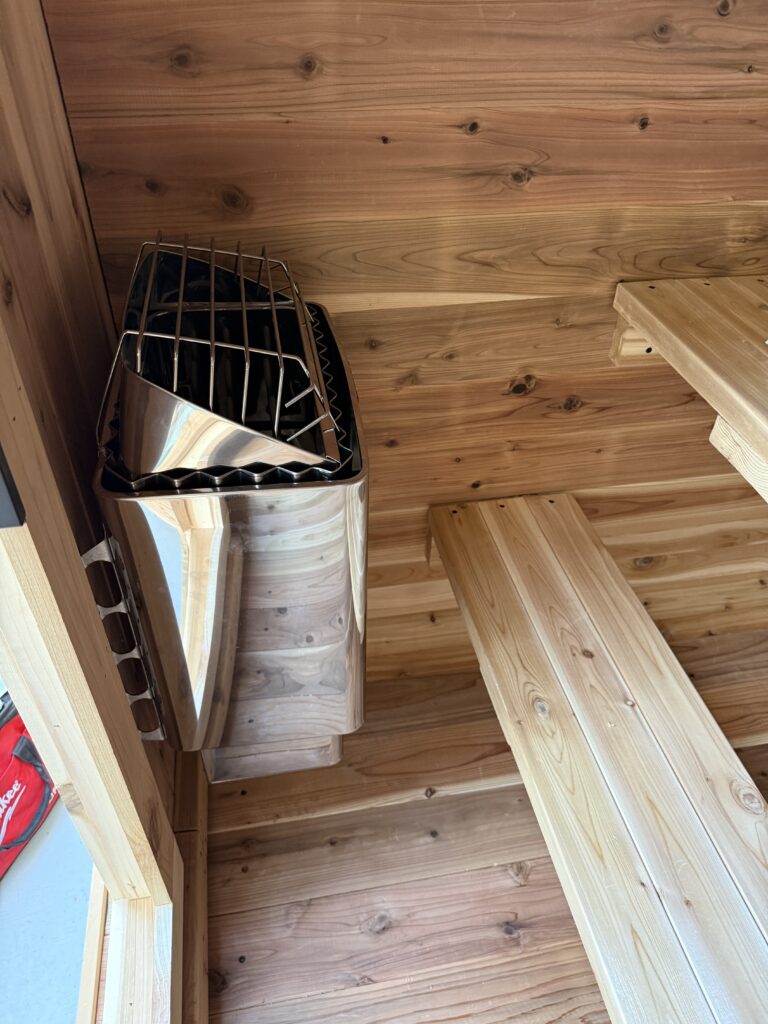 “Installed 220V sauna heater with protective grill and wood interior – Brentwood Electrical Experts, Los Angeles.”